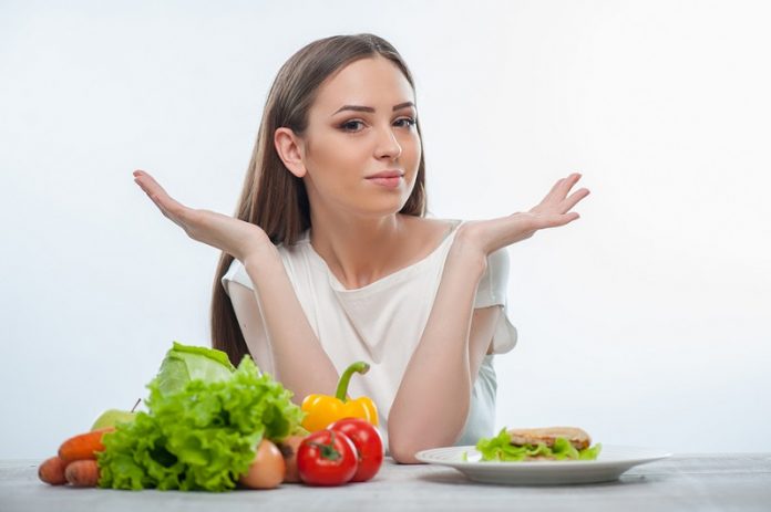 Pretty young woman does not know what to eat