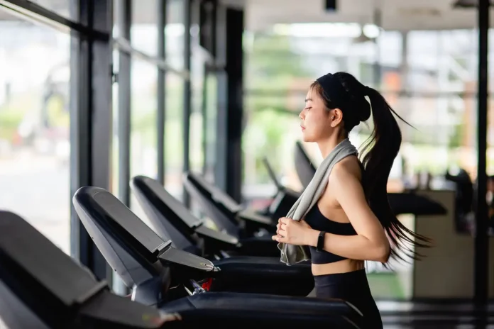 016247900_1765259781-young-sexy-woman-wearing-sportswear-sweat-proof-fabric-smartwatch-running-treadmill-workout-modern-gym-smile-copy-space