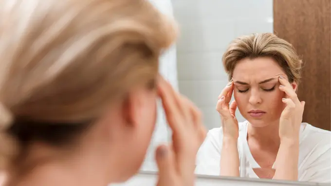 021020800_1779335035-woman-looking-mirror-having-headache_1_