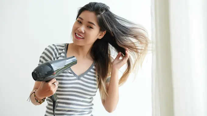 039985600_1750758674-waist-up-shot-asian-girl-blow-drying-her-hair-home